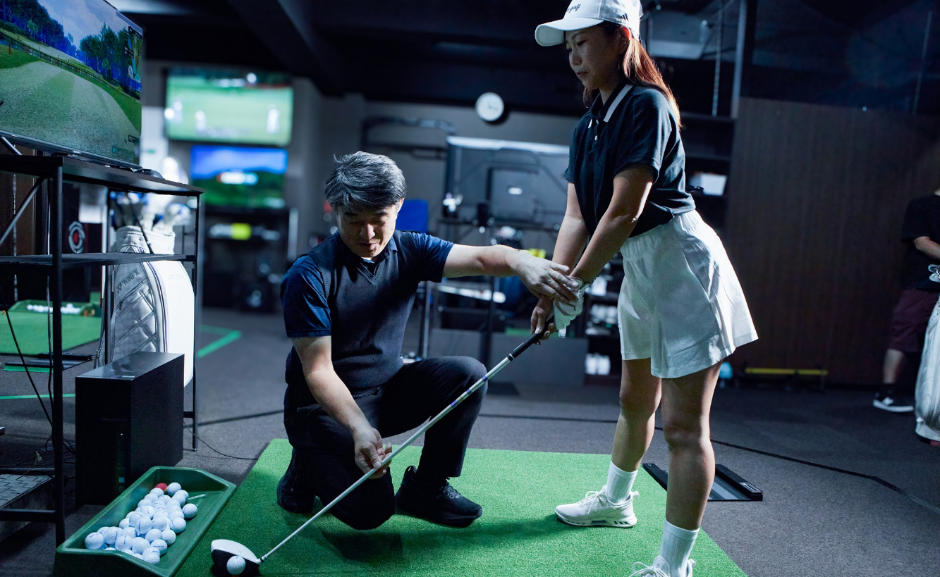 女性ゴルファーがマンツーマンでフォームをチェックするレッスン風景